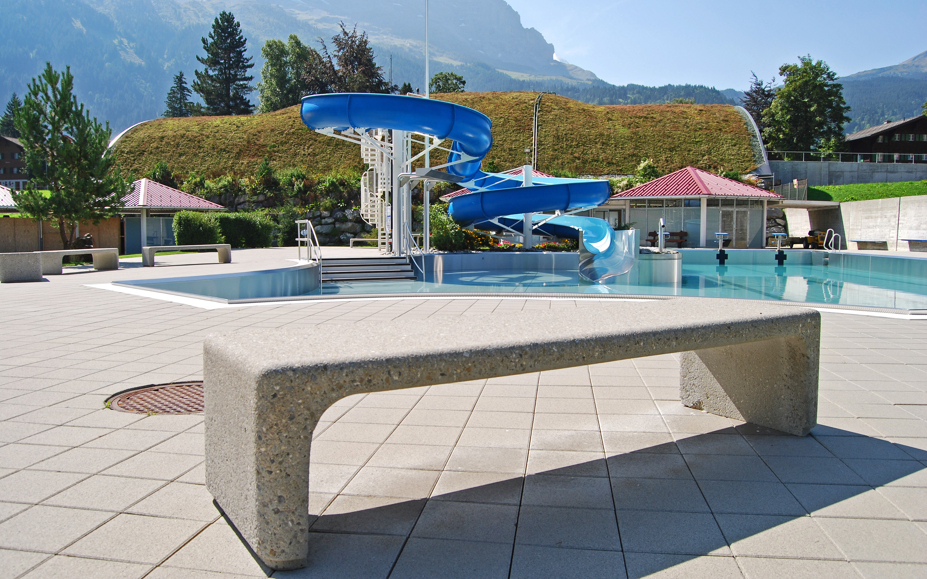 Outdoor swimming pool and building with a sloped green roof